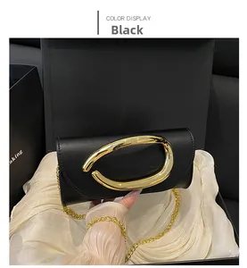 Detail of black leather clutch box bag featuring a bold gold metal oval buckle