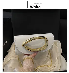 Detailed shot of a white faux leather clutch featuring a large golden horseshoe buckle