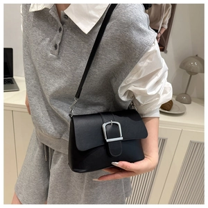 Detail of minimalist black crossbody bag with silver buckle and matte leather texture
