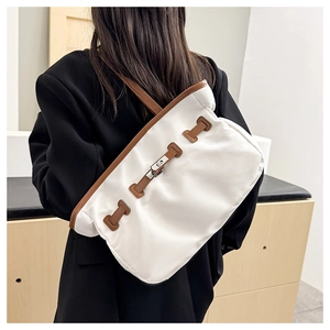 Détail du grand sac cabas blanc montrant le fermoir rotatif et les finitions en cuir marron