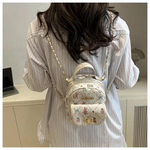 Detail eines schicken bedruckten Rucksacks mit Kettenriemen und goldenen Metallteilen