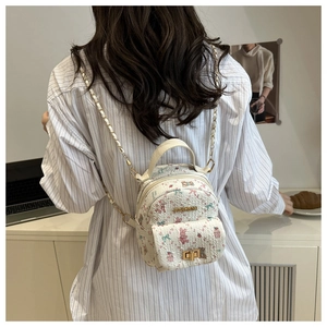 Detailed view of white textured mini backpack with pink bear and floral pattern details