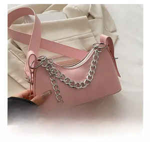 Detailed view of pink crescent bag with chunky silver chain on beige blazer