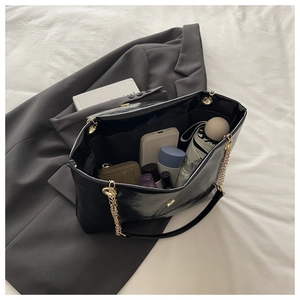 Interior view of black patent leather tote bag with gold chain showing large capacity