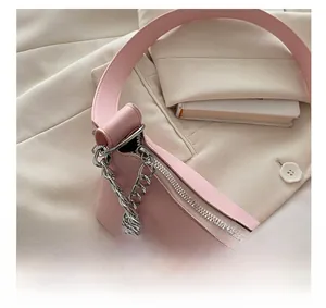 Close-up of smooth silver zipper and metal chain on light pink leather handbag
