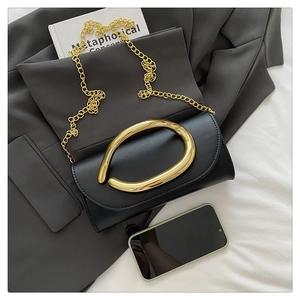 Close-up of black leather flap handbag with gold metal handle and chain strap