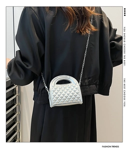 Silver metallic quilted mini bag with chain strap shown on model against dark background