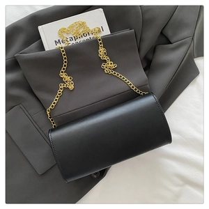 Detail of black faux leather flap bag with gold chain strap on a stylish blazer