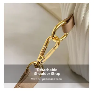Detail showing the detachable khaki shoulder strap with gold hardware on white leather bag