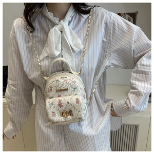 Detail of floral rabbit pattern, golden lock and chain strap on white crossbody bag