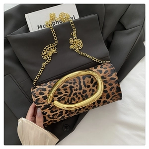Close-up of leopard print evening clutch with gold oval handle and chain strap on blazer