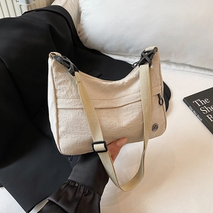 Minimalist beige nylon crescent crossbody bag with adjustable strap and metal logo detail