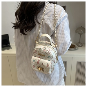 Detailansicht eines weißen Mini-Rucksacks mit Blumenmuster und goldener Kette