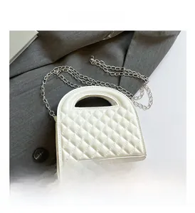 Macro view of white quilted leather bag detailing silver chain and handle texture
