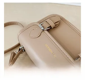 Detail shot of beige faux leather handbag with silver buckles and golden fashion text