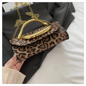 Detail of leopard print handbag with a gold curved handle and chain strap on a black blazer