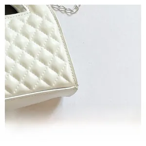 Macro shot of white quilted leather texture and silver chain strap on a handbag