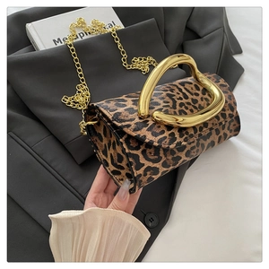 Detailed view of leopard print clutch with unique gold metal handle and chain strap