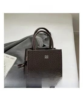 Close-up of coffee brown tote bag featuring snakeskin texture and min min metal logo