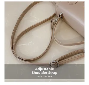 Detail of adjustable beige faux leather shoulder strap with silver metal buckles and stitching