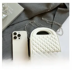 Detailed comparison of a white quilted mini handbag next to a smartphone showing size