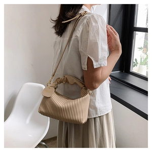 Detail of pleated beige cloud bag showing vertical texture and adjustable shoulder strap