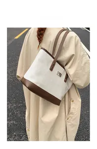 Vista dall'alto di una borsa tote bicolore minimalista con cinturini in pelle marrone su strada