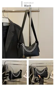 Detail of black crescent shoulder bag with chunky silver chain and brand pendant charm