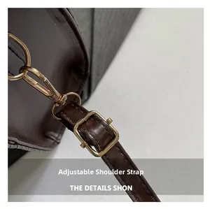 Detail view of adjustable leather shoulder strap with gold-tone buckle on brown bag