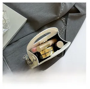 Internal storage view of small white quilted bag holding cosmetics and silver chain