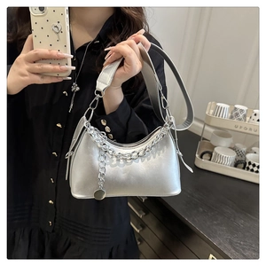 Detail of silver crossbody bag featuring thick shoulder strap and decorative metal chain
