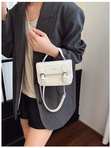 Detail of white Cambridge bag featuring double buckles and Fashion & Bag lettering