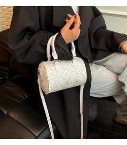 Detail of white embroidered barrel bag with floral patterns and sleek metal zipper