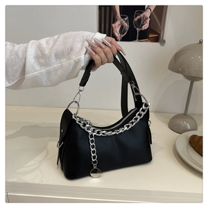 Detail of a black matte crescent bag with silver chain and thin strap in home setting