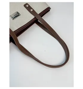 Dettaglio della borsa tote in tela con trama beige e manico in pelle marrone