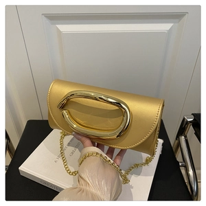 Detail of elegant gold evening clutch with oval metal handle and fine chain strap