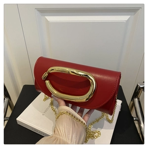 Detail of red leather evening bag with oversized gold metal ring handle and chain strap