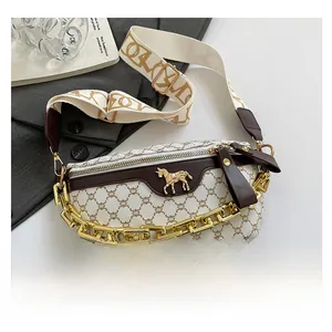 Close-up of saddle bag with gold horse emblem, chain detail and wide woven strap