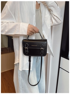 Detail showing black leather handbag with white contrast stitching and buckle design