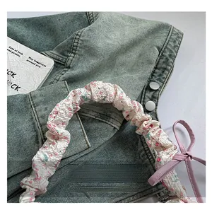Detail of floral scrunchie handle with pink bow on a stylish shoulder bag