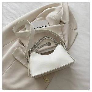 Detail of white minimalist underarm bag with silver chain and smooth leather texture