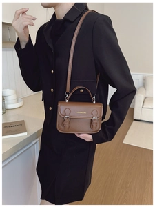 Detail showing vintage brown flap bag with gold buckle hardware and adjustable strap