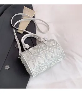 Detailed view of grey embroidered bucket bag with geometric patterns and leather straps