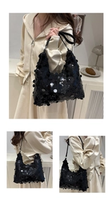 Detail of black sequined hobo bag featuring reflective sequins and leather shoulder strap