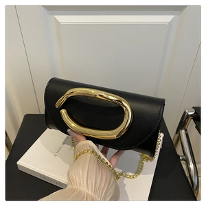 Close-up of black leather clutch bag featuring a large oval gold metal handle and chain