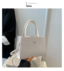 Detail of white woven texture shoulder bag with gold logo and elegant top handles