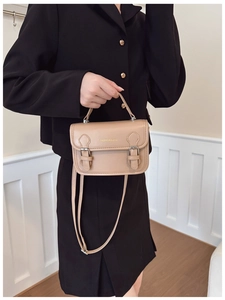 Detail of khaki PU leather bag with gold fashion lettering and adjustable shoulder strap