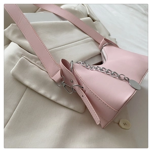 Pink PU leather shoulder bag with silver chain detail on beige blazer fabric