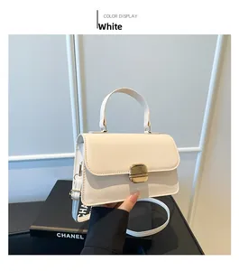 Detail van witte leren handtas met gouden vierkante sluiting en schouderband