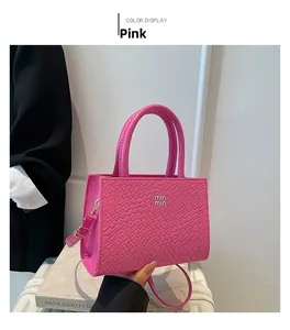 Detailed view of pink woven texture handbag featuring logo and adjustable strap